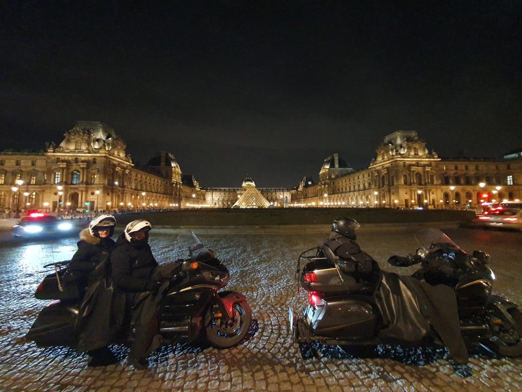 Balade à moto de nuit devant le Louvre illuminé à Paris